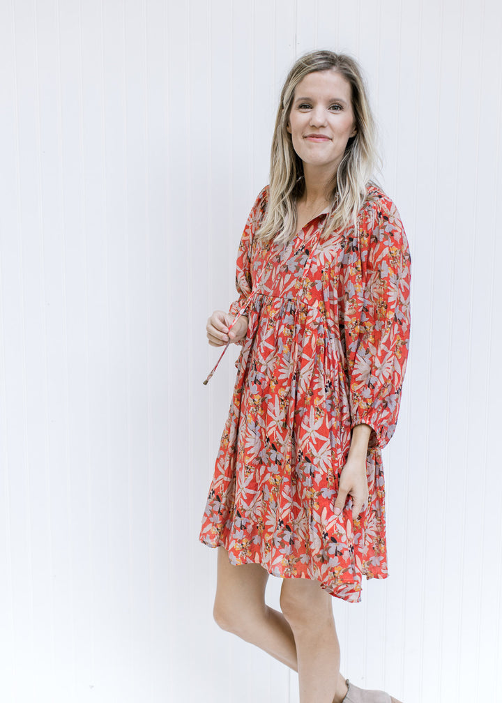 Model wearing a rust above the knee dress with 3/4 sleeves, a v-neck with a tie and fully lined. 