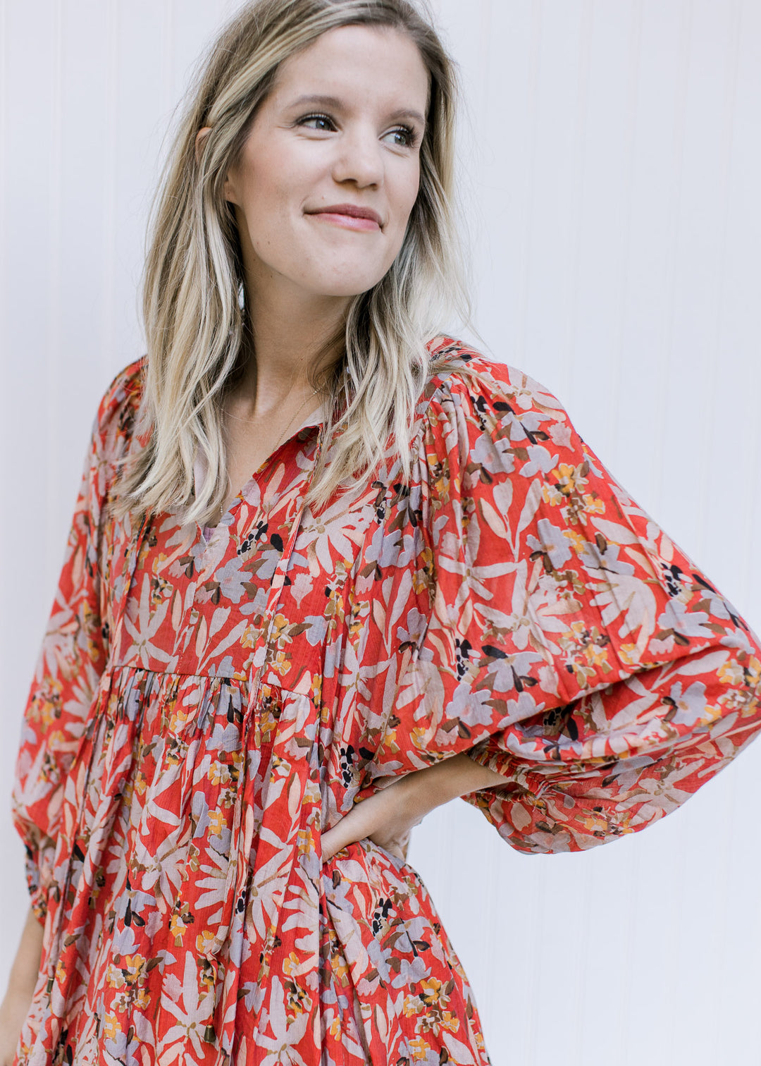 Close up of v-neck with a tie and semi-sheer 3/4 sleeves on a rust above the knee dress with floral.