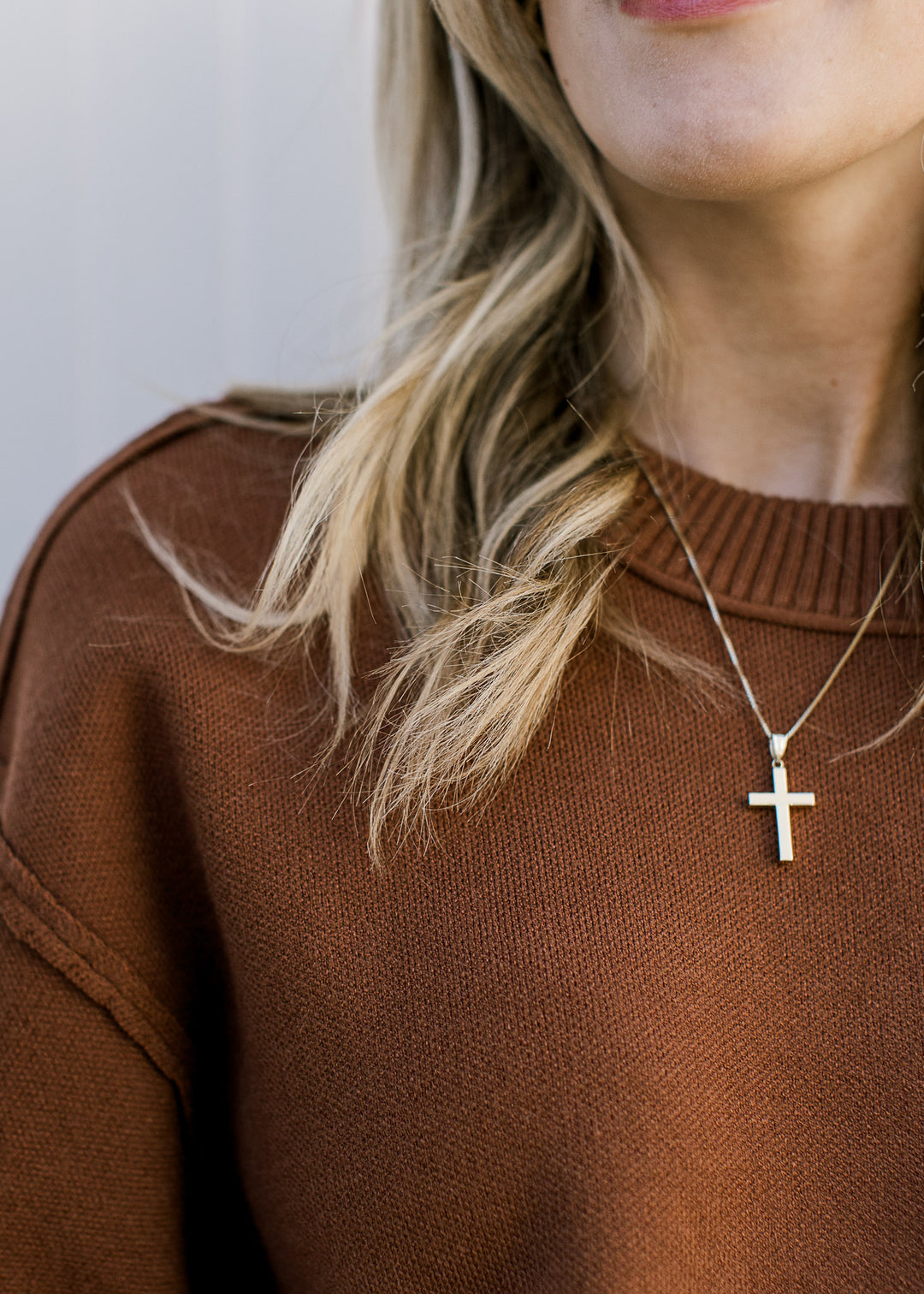 Closet up of expose hem and ribbing detail on a short sleeve rusty brown sweater with exposed hem. 