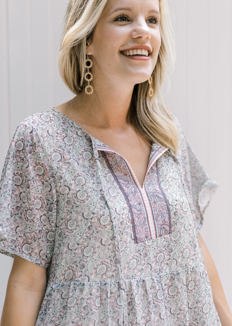 Close up view of tie on v-neck of pink, sage and cream dress with short sleeves. 