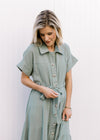 Close up of collar, short sleeves and tie belt on a gauze sage green maxi with a button front. 