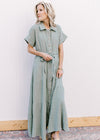 Model wearing a short sleeve sage maxi with gauze material, button front closure and a tie belt. 