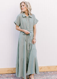 Model wearing a short sleeve sage maxi with gauze material, button front closure and a tie belt. 