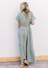 Back view of Model wearing a short sleeve sage maxi with gauze material and a tie belt. 