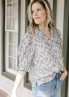 Model wearing a cream top with sage and pink floral, short puff sleeves and exaggerated collar.