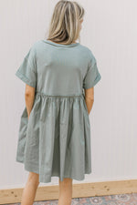 Back view of Model wearing a sage above the knee dress with contrasting material and short sleeves