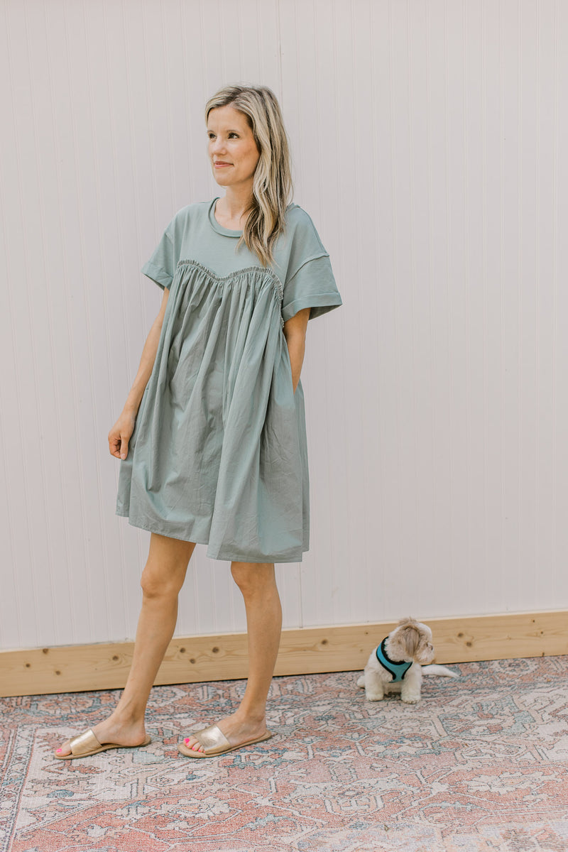 Model wearing sandals and a sage above the knee dress with contrasting material and short sleeves