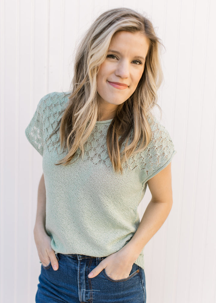 Model wearing a sage short sleeve sweater with knit detailing at the bodice and capped sleeves. 