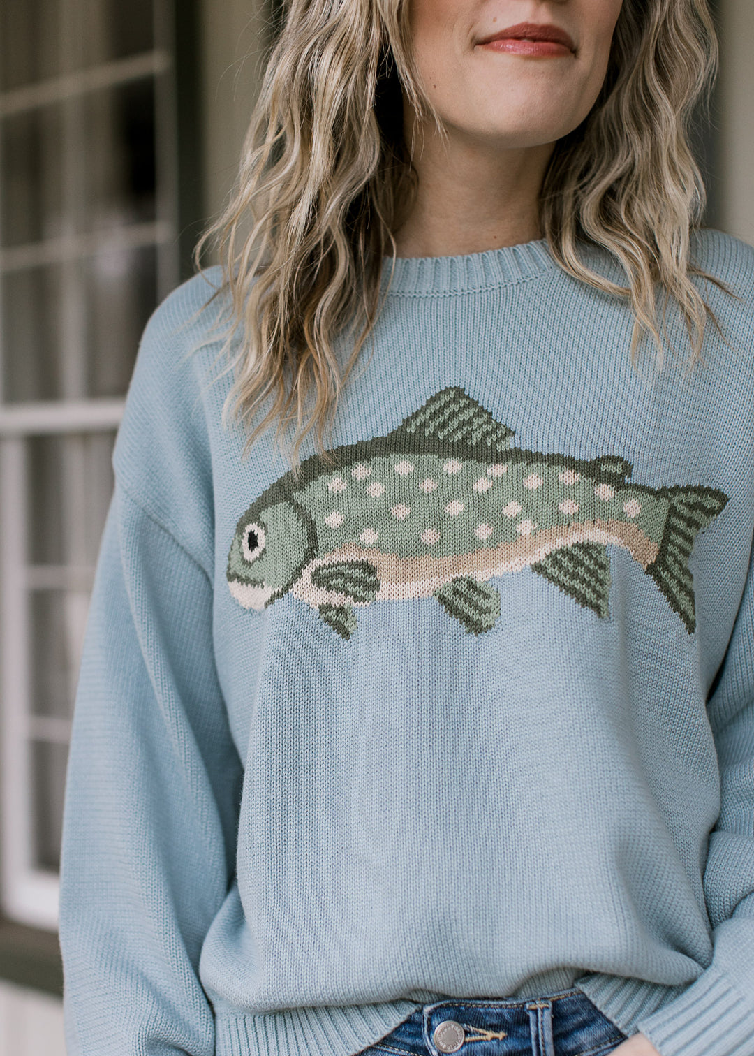 Close up of sage fish graphic with cream polka dots on a pale blue long sleeve sweater. 