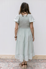 Back view of smocked bodice and short bubble sleeves on a soft sage midi with a polyester material. 
