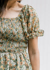 Model wearing a sage top with orange, pink and blue floral, smocked bodice and bubble short sleeves.