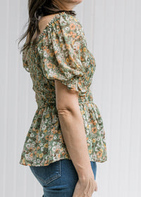 Side view of bubble short sleeve and smocked bodice on a sage top with orange, pink and blue floral.