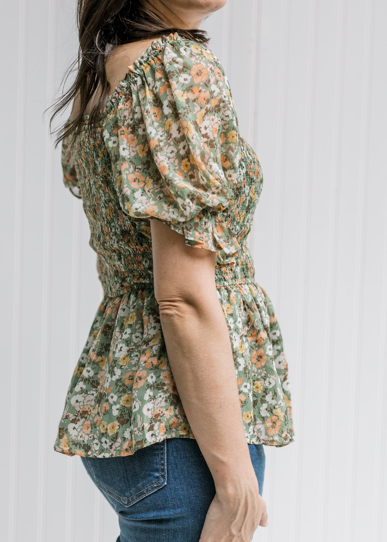 Side view of bubble short sleeve and smocked bodice on a sage top with orange, pink and blue floral.