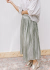 Model wearing a sage maxi skirt with an elastic waist band and comprised of polyester. 