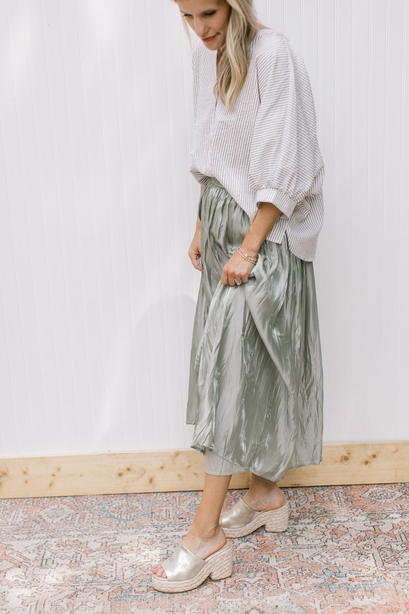 Model wearing  a sage maxi skirt with crinkle fabric, lining and elastic waist. 