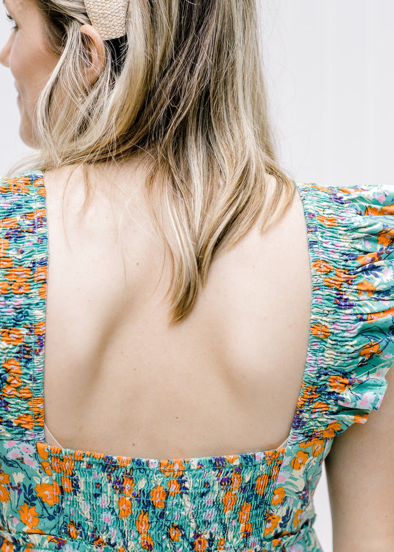 Close up of square back on a sage dress with an orange, blue and purple floral pattern. 