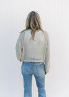 Back view of Model wearing a sage open weave sweater with long sleeves and a round neck.