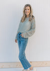 Model wearing jeans with a sage open weave sweater with long sleeves and a slightly cropped fit.
