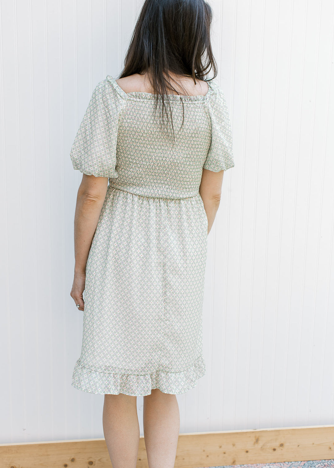 Back view of Model wearing a sage dress with cream and rust pattern and smocked bodice. 