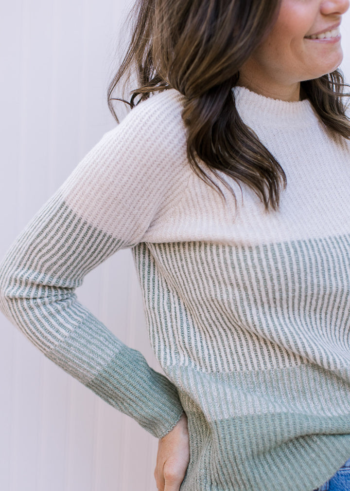 Close up of ribbing on a cream and sage ribbed sweater with long sleeves and round neck. 
