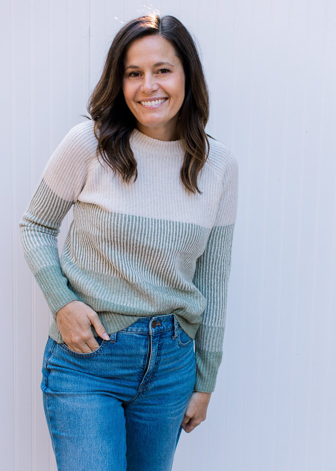 Model wearing a cream to sage ombre ribbed sweater with long sleeves and a round neck.