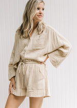 Model wearing a sand colored set, shorts with a paper bag drawstring closure, top is  a button up. 