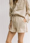 Close up of shorts with a paper bag drawstring closure on a sand colored set.