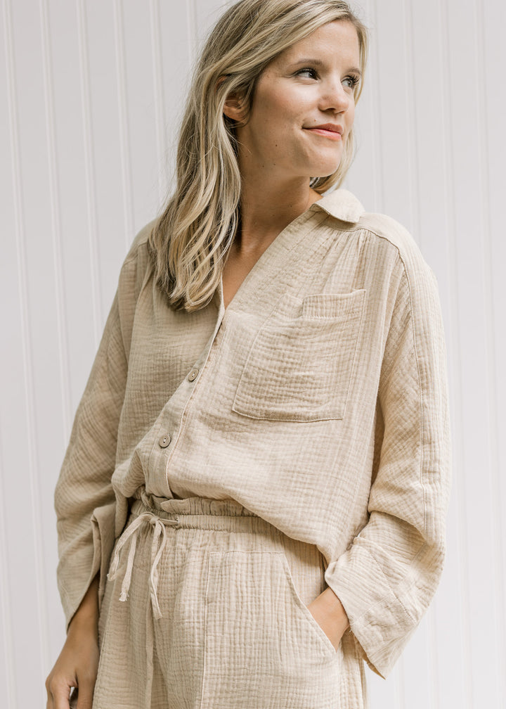 Model wearing a sand set with a button up top with dolmain sleeves and shorts.