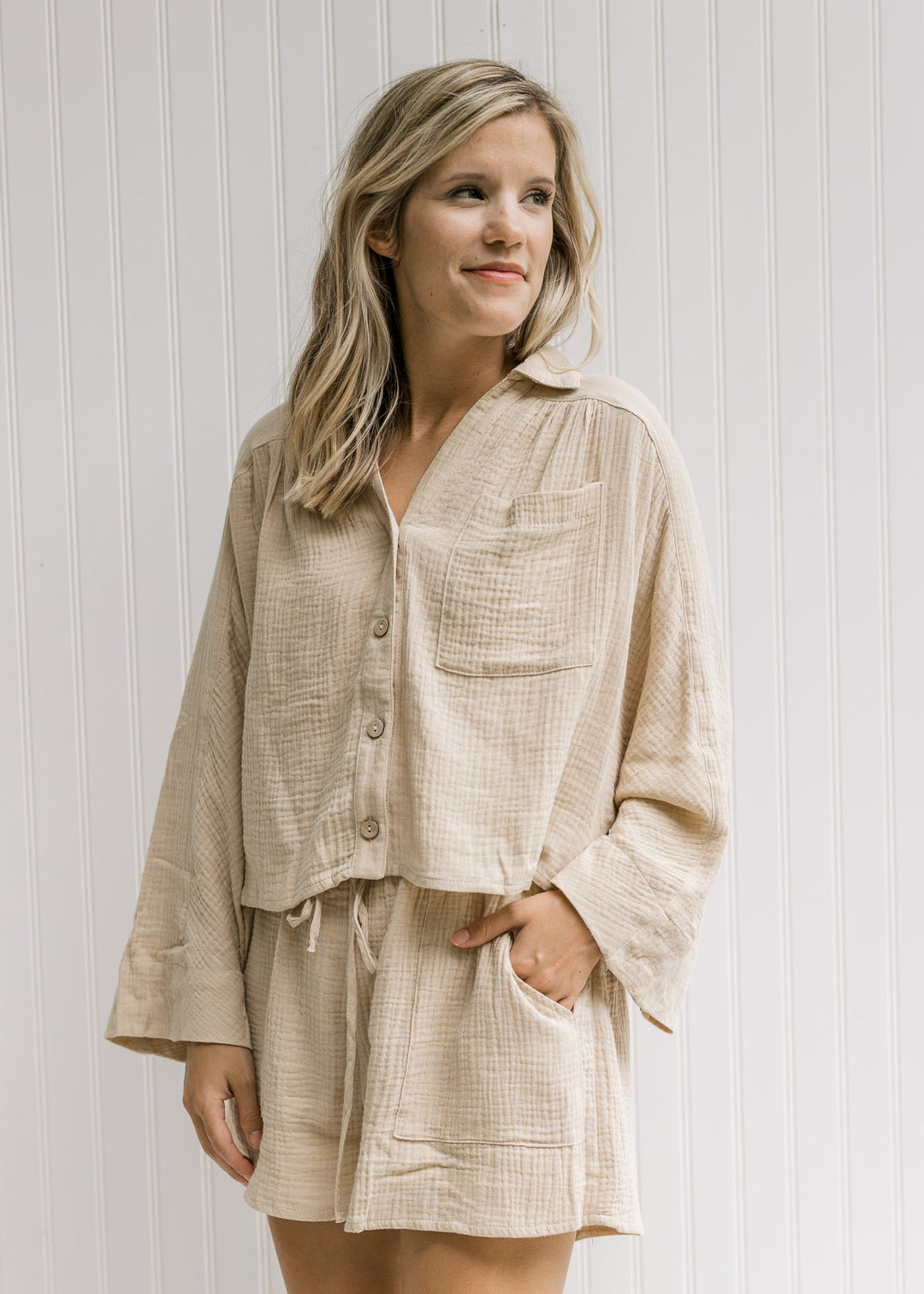 Model wearing a sand top with a patch pocket, a button closure and shorts. 