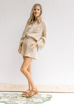 Model wearing shorts with a sand color short set  with a button up top and dolmain sleeves.