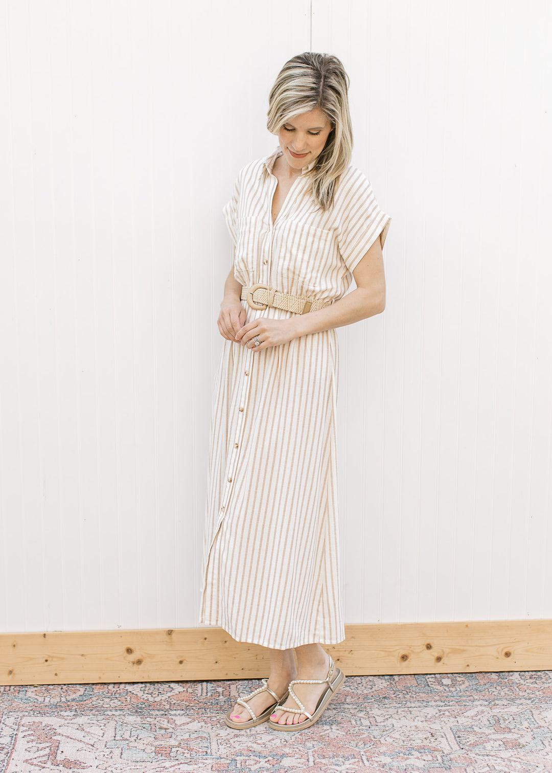 Model wearing a cream midi with sand stripes, button front, collar and elastic waist with belt.