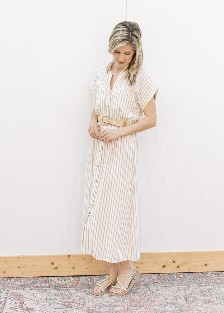 Model wearing a cream midi with sand stripes, button front, collar and elastic waist with belt.