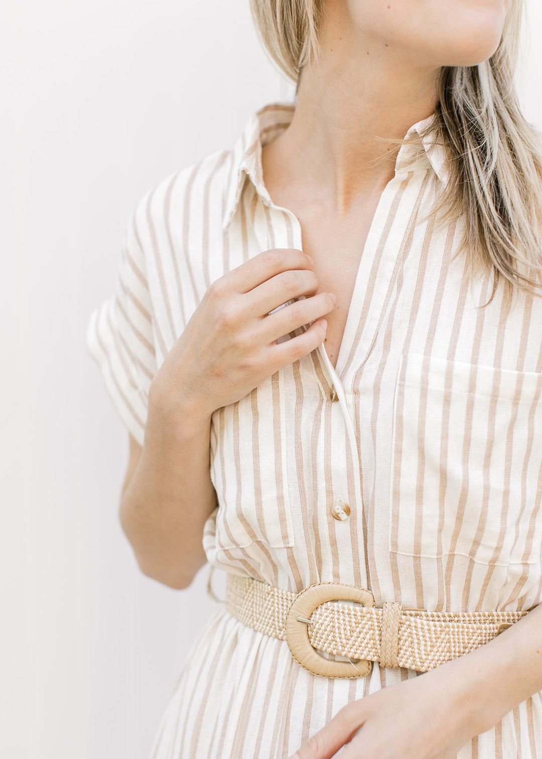 Close up of v-neck, collar and patch pockets on a cream button up midi with sand stripes. 