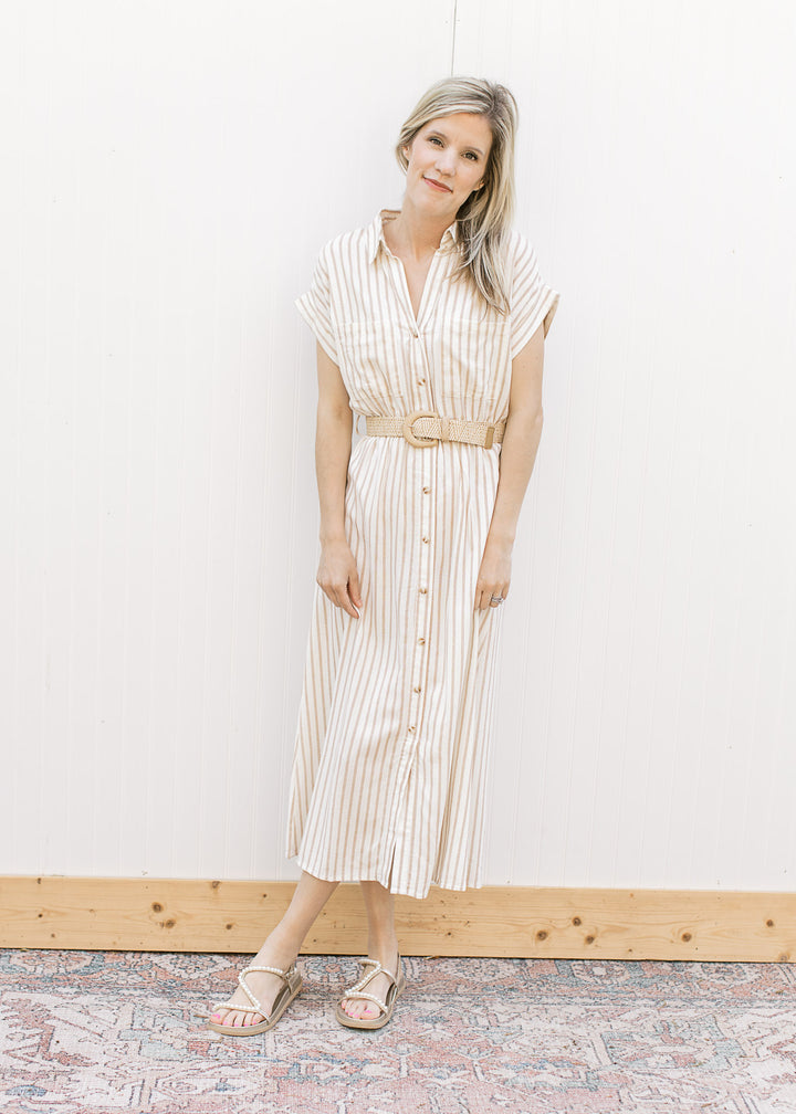 Model wearing sandals and a cream midi with sand stripes, buttons, collar and a belt.