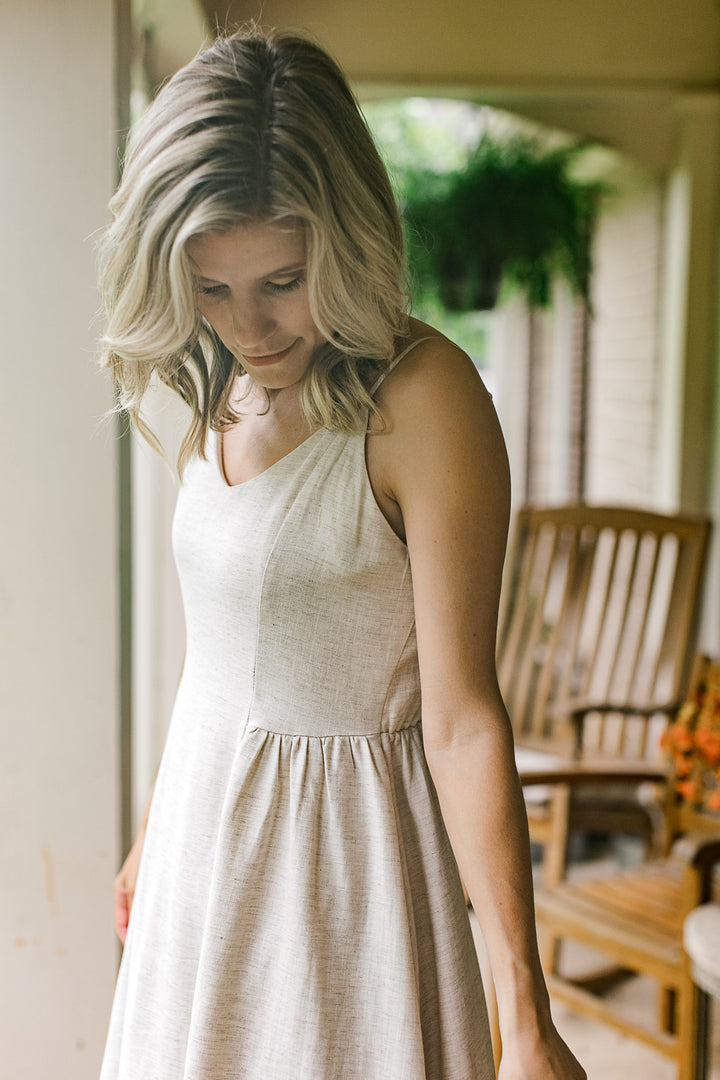 Side view of pleating detail on a sand midi with spaghetti straps, v-neck and a smocked back.