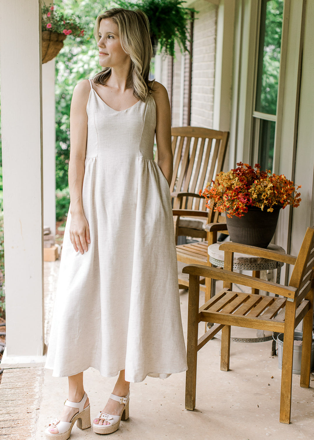 Model wearing heels and a sand midi with spaghetti straps, v-neck and a smocked back panel.