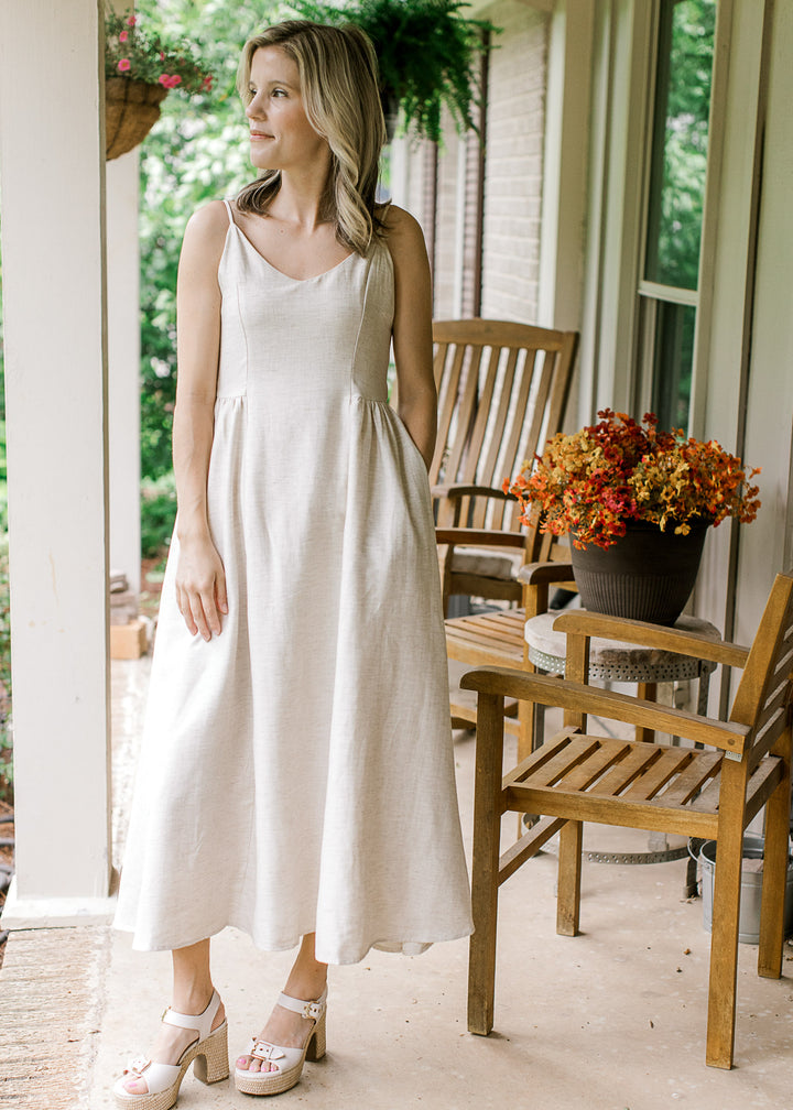 Model wearing heels and a sand midi with spaghetti straps, v-neck and a smocked back panel.