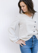 Model wearing a cream polyester top with bubble long sleeves and a side button detail.