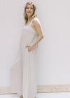 Model wearing a sand colored jumpsuit with wide legs, pockets and adjustable button straps. 
