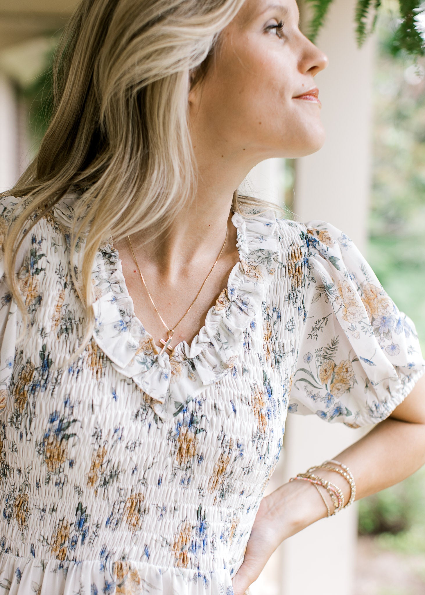 Close up of smocked bodice, v-neck with a ruffle and sheer bubble sleeves on a hite floral dress.