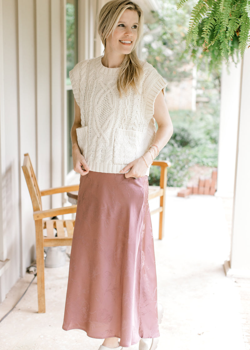 Model wearing a cream top and a chestnut maxi with subtle floral pattern and a satin material. 