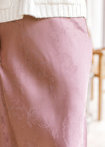 Close up of a chestnut maxi with subtle floral pattern, a satin material and a side zipper.