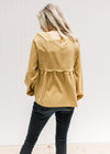 Back view of Model wearing a mustard top with a scalloped detail, square neckline and long sleeves.