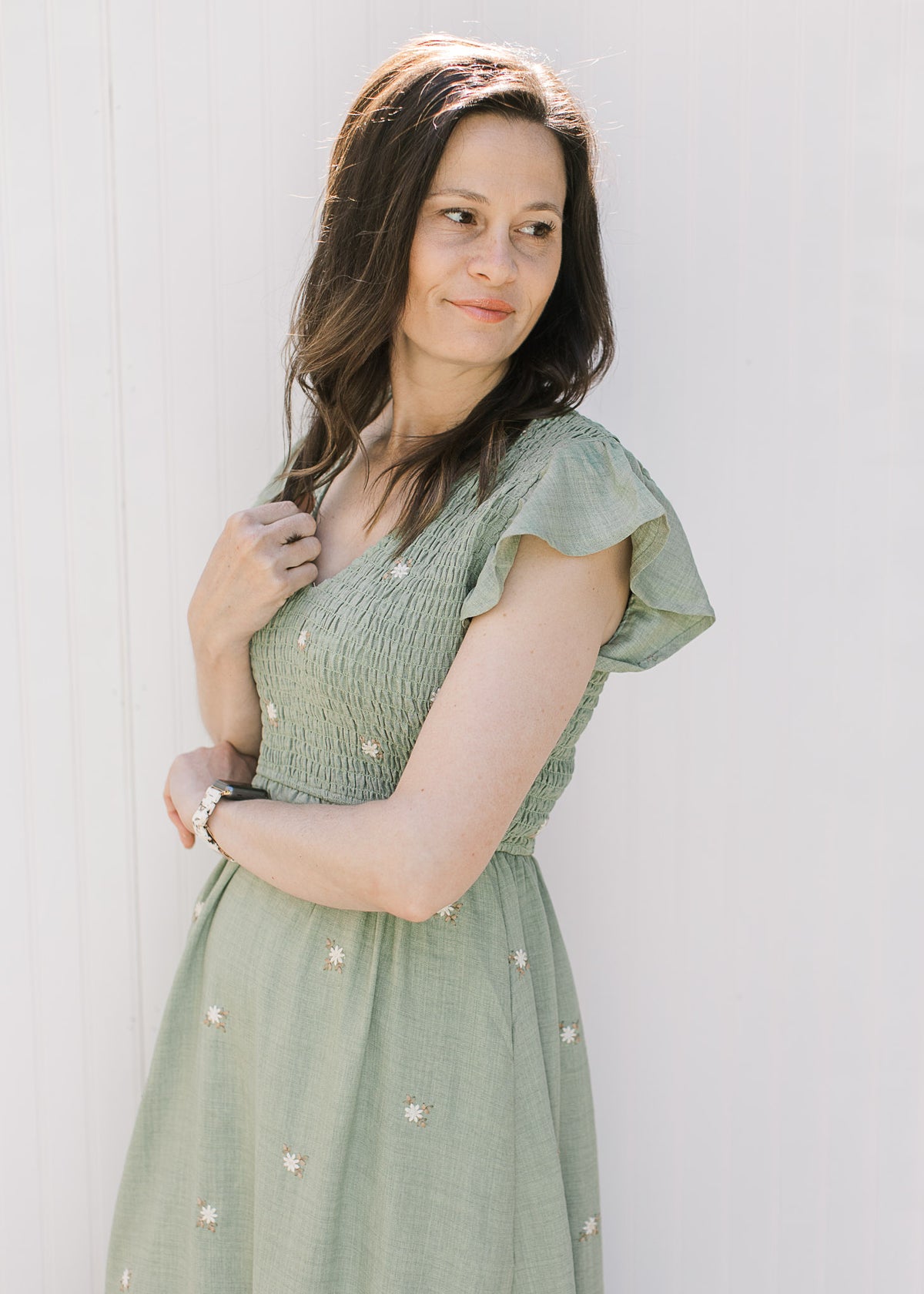 Close up of smocked bodice, v-neck and flutter cap sleeves on a sage midi with cream flowers. 