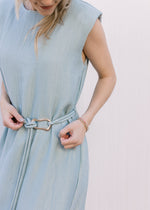 Close up of tie belt on a model wearing a sleeveless seafoam dress with shoulder pads. 