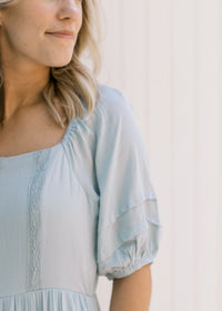 Close up view of bubble short sleeves and lace detail on the bodice of a seafoam maxi dress. 
