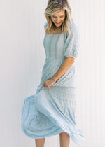 Model twirling in a seafoam colored maxi dress with short sleeves and lace detail on the bodice. 