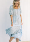 Model turning in a seafoam colored maxi dress with short sleeves and lace detail on the bodice. 