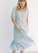 Model twisting in a seafoam colored maxi dress with short sleeves and lace detail on the bodice. 