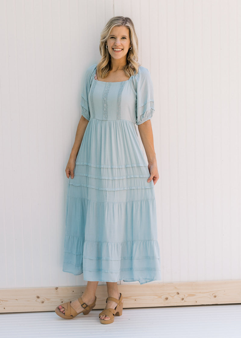 Model wearing heels with a seafoam colored maxi dress with bubble short sleeves and lace detail. 